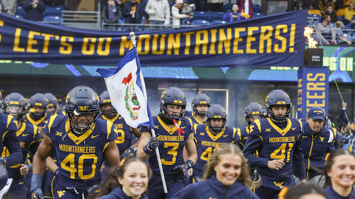 Nov 23, 2024; Morgantown, West Virginia, USA; West Virginia Mountaineers wide receiver Hudson Clement (3) carries the West Virginia state flag as he leads his team onto the field before a game against the UCF Knights at Mountaineer Field at Milan Puskar Stadium. Mandatory Credit: Ben Queen-Imagn Images