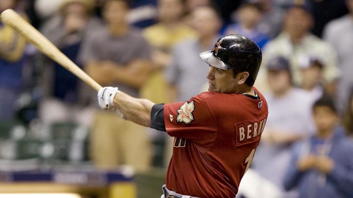 Former Houston Astros player Lance Berkman swings the bat wearing a red jersey and black helmet.