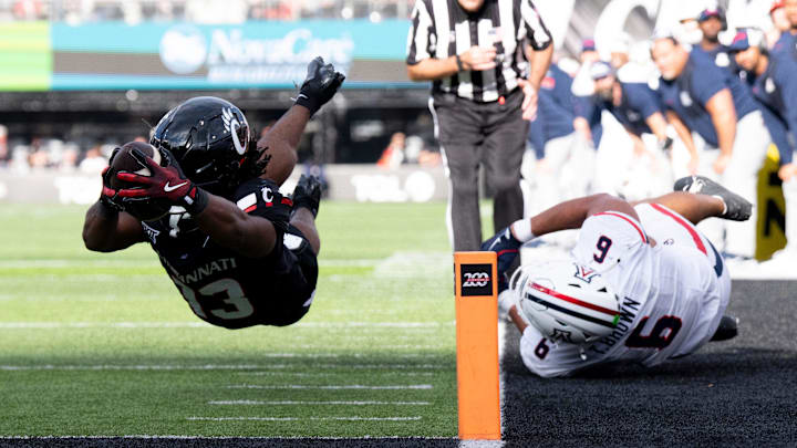 Cincinnati Bearcats running back Zion Johnson (13) catches a pass and runs for a first down on fourth down as Arizona Wildcats defensive back Ayden Garnes (9) tackles him in the fourth quarter of the NCAA football game between the Cincinnati Bearcats and Arizona Wildcats at Nippert Stadium in Cincinnati on Nov. 15, 2025.