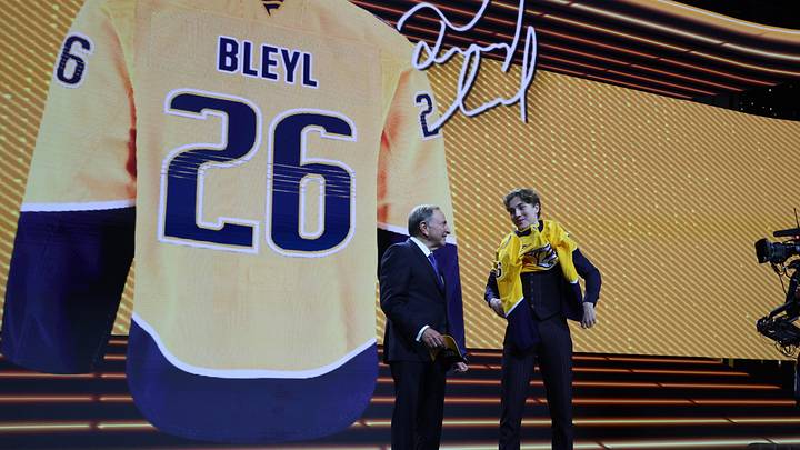 Jun 26, 2026; Buffalo, New York, USA; Tommy Bleyl reacts beside NHL commissioner Gary Bettman after being selected with the thirty first pick in the first round of the 2026 NHL Draft by the Nashville Predators at KeyBank Center. Mandatory Credit: Timothy T. Ludwig-Imagn Images