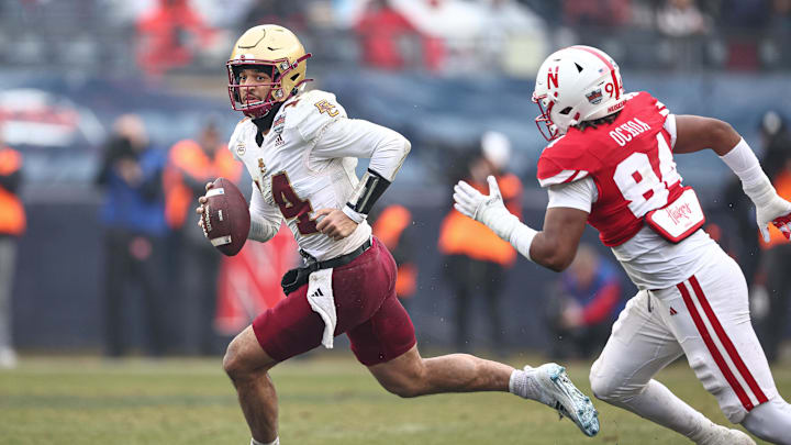 Dec 28, 2024; Bronx, NY, USA; Boston College Eagles quarterback Grayson James (14) scrambles as Nebraska Cornhuskers defensive end Jordan Ochoa (94) pursues during the first half at Yankee Stadium. Mandatory Credit: Vincent Carchietta-Imagn Images