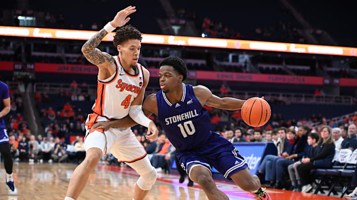 Dec 22, 2025; Syracuse, New York, USA; Stonehill Skyhawks Guard Hermann Kooffi (10) drives the ball as Syracuse Orange Guard Nate Kingz (4) defends the baseline in the first half at the JMA Wireless Dome. Mandatory Credit: Mark Konezny-Imagn Images