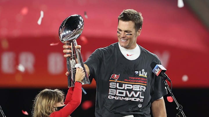 Tampa Bay Buccaneers quarterback Tom Brady (12) hoists the Vince Lombardi Trophy with his daughter, Vivian, after defeating the Kansas City Chiefs in Super Bowl LV.