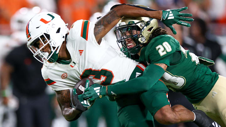 Sep 21, 2024; Tampa, Florida, USA; Miami Hurricanes wide receiver Jacolby George (3) is tackled by South Florida Bulls cornerback Brent Austin (20) in the first quarter at Raymond James Stadium. Mandatory Credit: Nathan Ray Seebeck-Imagn Images Sep 21, 2024; Tampa, Florida, USA; Miami Hurricanes wide receiver Jacolby George (3) is tackled by South Florida Bulls cornerback Brent Austin (20) in the first quarter at Raymond James Stadium. Mandatory Credit: Nathan Ray Seebeck-Imagn Images