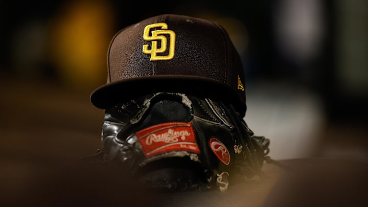 Jun 17, 2022; Denver, Colorado, USA; A detail view of a San Diego Padres hat on a glove in the dugout in the ninth inning against the Colorado Rockies at Coors Field. Mandatory Credit: Isaiah J. Downing-Imagn Images