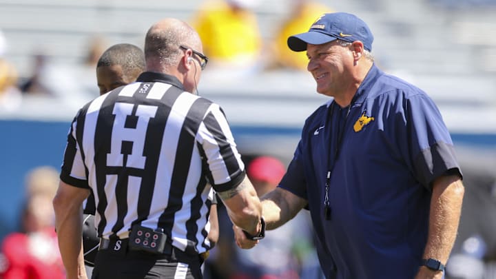 Aug 30, 2025; Morgantown, West Virginia, USA; West Virginia Mountaineers head coach Rich Rodriguez shakes hands with a referee before the game against the Robert Morris Colonials at Milan Puskar Stadium. Mandatory Credit: Ben Queen-Imagn Images