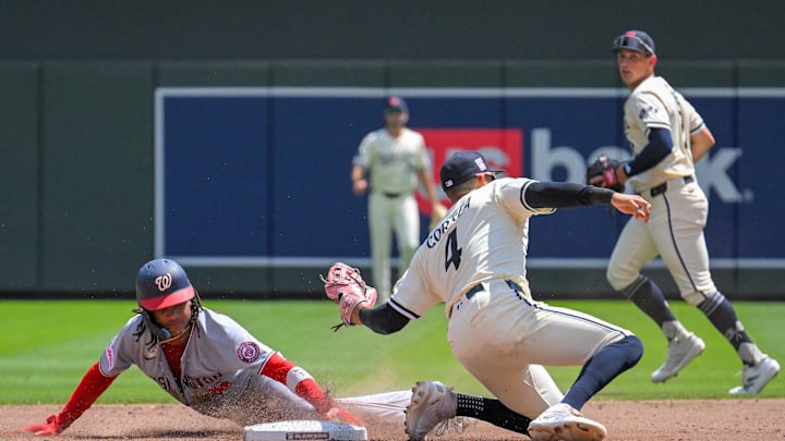 Jul 27, 2025; Minneapolis, Minnesota, USA;  Washington Nationals infielder C.J. Abrams (5) beats the tag attempt of Minnesota Twins infielder Carlos Correa (4) for a stolen base during the third inning at Target Field. Mandatory Credit: Nick Wosika-Imagn Images