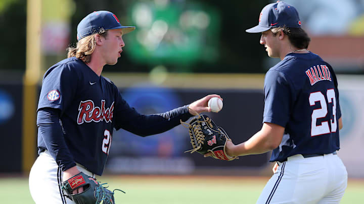Jun 12, 2022; Hattiesburg, MS, USA; Ole Miss pitcher Hunter Elliott (26) hands the ball to relief pitcher Josh Mallitz (23) in the eighth inning against Southern Miss during Game 2 of a NCAA Super Regional game at Pete Taylor Park. Ole Miss won, 5-0, and advanced to the College World Series. Mandatory Credit: Chuck Cook-Imagn Images Jun 12, 2022; Hattiesburg, MS, USA; Ole Miss pitcher Hunter Elliott (26) hands the ball to relief pitcher Josh Mallitz (23) in the eighth inning against Southern Miss during Game 2 of a NCAA Super Regional game at Pete Taylor Park. Ole Miss won, 5-0, and advanced to the College World Series. Mandatory Credit: Chuck Cook-Imagn Images