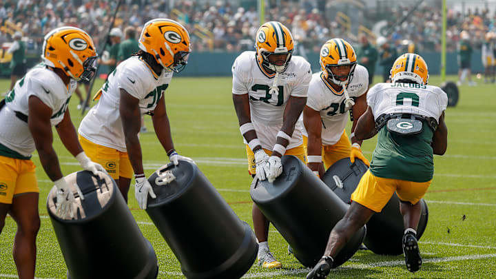 Green Bay Packers running backs move trash cans to simulate the offensive line creating a hole for Josh Jacobs at training camp.