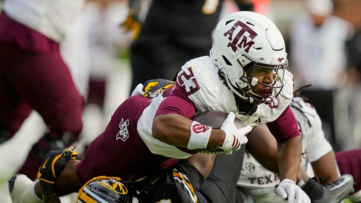 Nov 8, 2025; Columbia, Missouri, USA; Texas A&M Aggies running back Jamarion Morrow (23) dives forward against Missouri Tigers linebacker Triston Newson (14) during the first half at Faurot Field at Memorial Stadium. Mandatory Credit: Jay Biggerstaff-Imagn Images Nov 8, 2025; Columbia, Missouri, USA; Texas A&M Aggies running back Jamarion Morrow (23) dives forward against Missouri Tigers linebacker Triston Newson (14) during the first half at Faurot Field at Memorial Stadium. Mandatory Credit: Jay Biggerstaff-Imagn Images