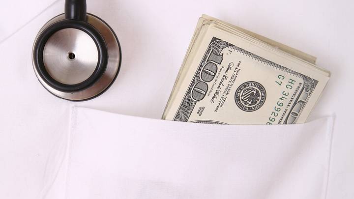 Doctor with $100 bills in their pocket