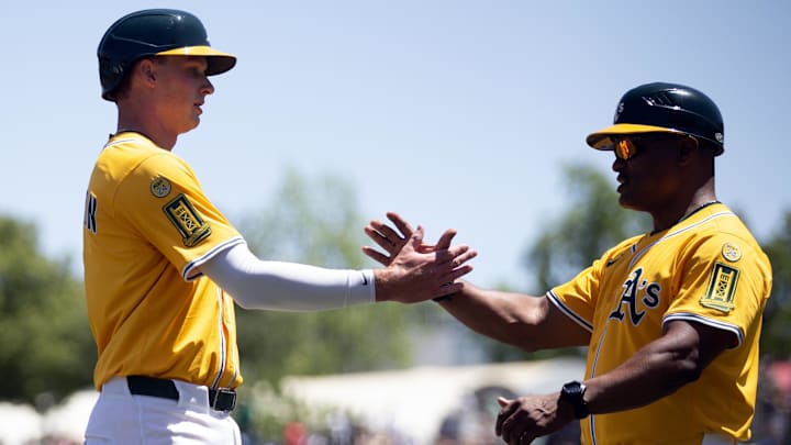 May 25, 2025; West Sacramento, California, USA; Athletics first baseman Logan Davidson (6) gets a congratulatory handshake from third base coach Eric Martins after getting his first hit and RBI against the Philadelphia Phillies during the first inning at Sutter Health Park. Mandatory Credit: D. Ross Cameron-Imagn Images