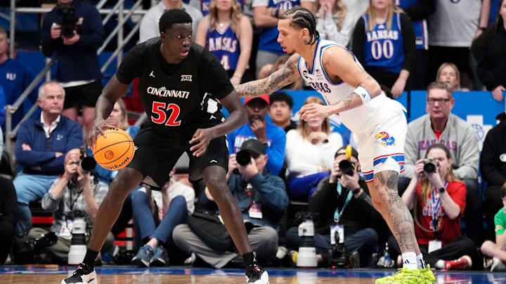 Feb 21, 2026; Lawrence, Kansas, USA; Cincinnati Bearcats center Moustapha Thiam (52) dribbles the ball as Kansas Jayhawks guard Jayden Dawson (1) defends during the second half of the game at Allen Fieldhouse. Mandatory Credit: Denny Medley-Imagn Images