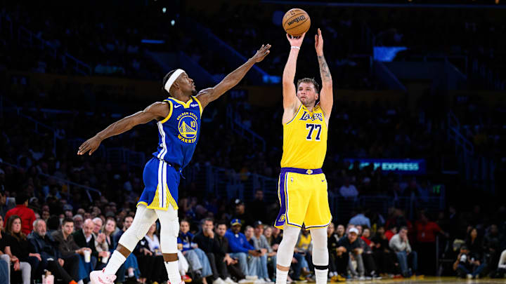 Oct 21, 2025; Los Angeles, California, USA; Los Angeles Lakers guard Luka Doncic (77) shoots over Golden State Warriors forward Jimmy Butler III (10) during the first half at Crypto.com Arena. Mandatory Credit: William Liang-Imagn Images