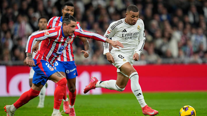 Kylian Mbappé and Jose Maria Gimenez tussle for the ball in a Madrid derby. 