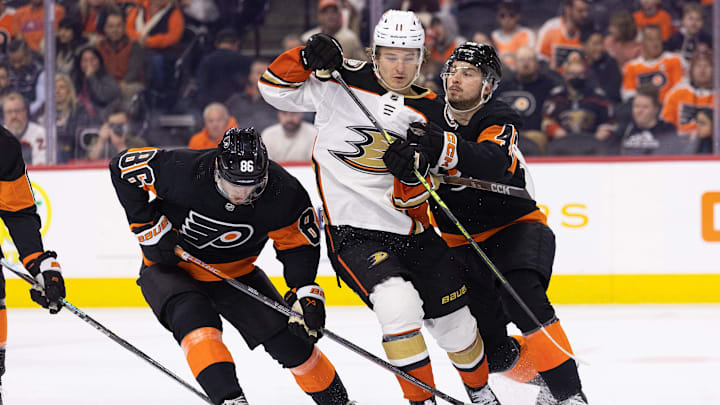 Jan 17, 2023; Philadelphia, Pennsylvania, USA; Anaheim Ducks center Trevor Zegras (11) is checked off the puck by Philadelphia Flyers left wing Noah Cates (49) and left wing Joel Farabee (86) during the second period at Wells Fargo Center. Mandatory Credit: Bill Streicher-Imagn Images