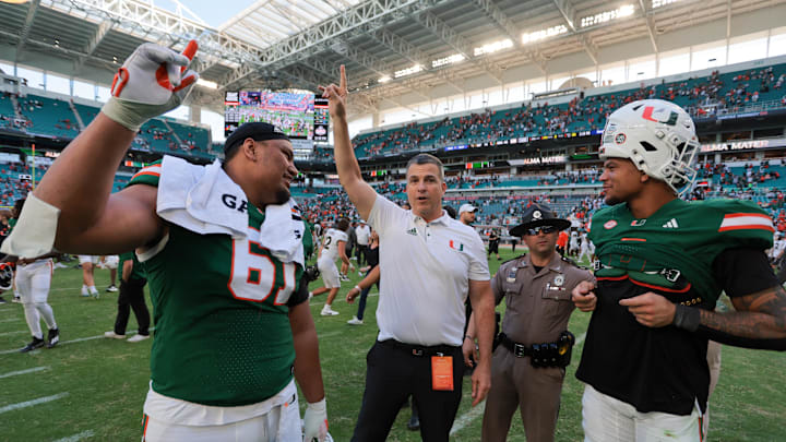 Nov 23, 2024; Miami Gardens, Florida, USA; Miami Hurricanes head coach Mario Cristobal celebrates with Miami Hurricanes offensive lineman Francis Mauigoa (61) and tight end Elijah Arroyo (8) after the game against the Wake Forest Demon Deacons at Hard Rock Stadium. Mandatory Credit: Sam Navarro-Imagn Images Nov 23, 2024; Miami Gardens, Florida, USA; Miami Hurricanes head coach Mario Cristobal celebrates with Miami Hurricanes offensive lineman Francis Mauigoa (61) and tight end Elijah Arroyo (8) after the game against the Wake Forest Demon Deacons at Hard Rock Stadium. Mandatory Credit: Sam Navarro-Imagn Images