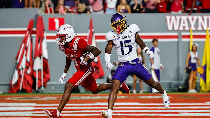Aug 28, 2025; Raleigh, North Carolina, USA; North Carolina State Wolfpack wide receiver Wesley Grimes (6) makes a touchdown past East Carolina Pirates defensive back Jordy Lowery (15) during the first half of the game at Carter-Finley Stadium. Mandatory Credit: Jaylynn Nash-Imagn Images