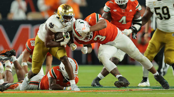 Aug 31, 2025; Miami Gardens, Florida, USA;  Notre Dame Fighting Irish running back Jadarian Price (24) rushes the ball past Miami Hurricanes defensive lineman Akheem Mesidor (3) during the second quarter at Hard Rock Stadium. Mandatory Credit: Sam Navarro-Imagn Images