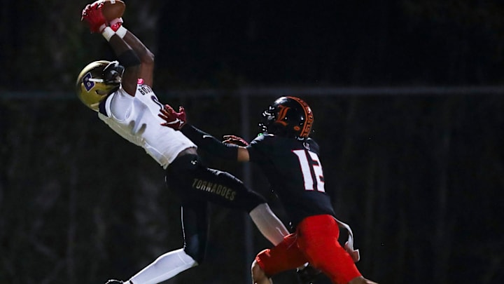 Sarasota Booker Tornadoes receiver Chauncey Kennon (0) stretches to make a catch as Lely Trojans defensive back Roberly Gamboa (12) covers him during the second quarter of a Week 5 game at Lely High School in Naples, Fla., on Friday, Sept. 19, 2025.