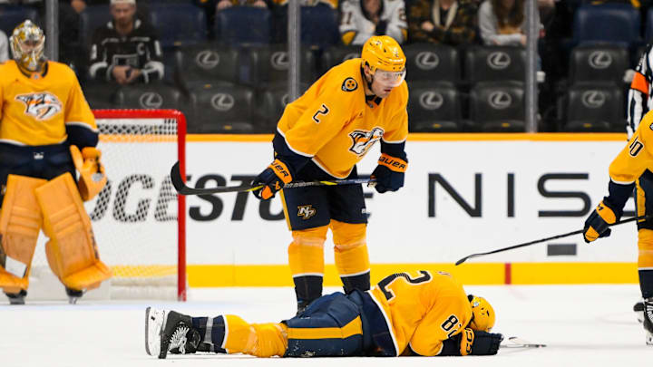 Nov 4, 2024; Nashville, Tennessee, USA;  Nashville Predators center Tommy Novak (82) lays face down after taking a puck to the face against the Los Angeles Kings during the third period at Bridgestone Arena. Mandatory Credit: Steve Roberts-Imagn Images