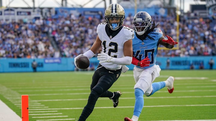 Dec 28, 2025; Nashville, Tennessee, USA; New Orleans Saints wide receiver Chris Olave (12) runs in a touchdown in front of Tennessee Titans cornerback Kemon Hall (40) during the third quarter  at Nissan Stadium. Mandatory Credit: Andrew Nelles-USA TODAY Network via Imagn Images