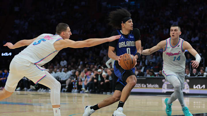 Jan 27, 2025; Miami, Florida, USA; Orlando Magic guard Anthony Black (0) drives to the basket against Miami Heat forward Nikola Jovic (5) and guard Tyler Herro (14) during overtime at Kaseya Center. Mandatory Credit: Sam Navarro-Imagn Images