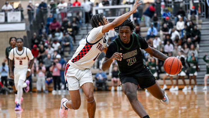 East Lansing's Brian Windham Jr., left, guards Ann Arbor Huron's Macari Moore during the first quarter on Tuesday, March 12, 2024, at Holt High School.