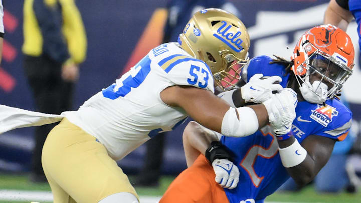 Dec 16, 2023; Inglewood, CA, USA; UCLA Bruins linebacker Darius Muasau (53) and defensive lineman Jake Heimlicher (51) tackle Boise State Broncos running back Ashton Jeanty (2) during first quarter of the Starco Brands LA Bowl at SoFi Stadium. Mandatory Credit: Robert Hanashiro-Imagn Images