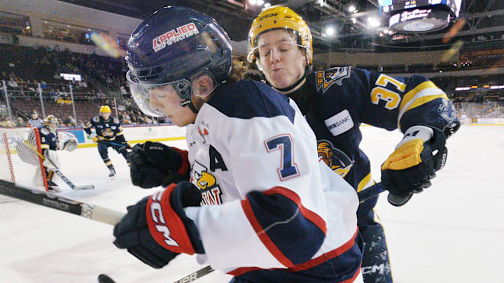Erie Otters defenseman Quinn McCall, right, checks Saginaw Spirit forward Calem Mangone during an Ontario Hockey League playoff game at Erie Insurance Arena in Erie on April 1, 2025.