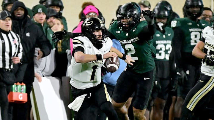 Nov 22, 2024; East Lansing, Michigan, USA;  Purdue Boilermakers quarterback Hudson Card (1) scrambles, under pressure from Michigan State Spartans defensive lineman Khris Bogle (2) during the third quarter at Spartan Stadium. Mandatory Credit: Dale Young-Imagn Images