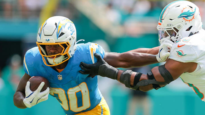 Oct 12, 2025; Miami Gardens, Florida, USA; Los Angeles Chargers running back Kimani Vidal (30) carries the football against Miami Dolphins linebacker Jordyn Brooks (20) during the first quarter at Hard Rock Stadium. Oct 12, 2025; Miami Gardens, Florida, USA; Los Angeles Chargers running back Kimani Vidal (30) carries the football against Miami Dolphins linebacker Jordyn Brooks (20) during the first quarter at Hard Rock Stadium.