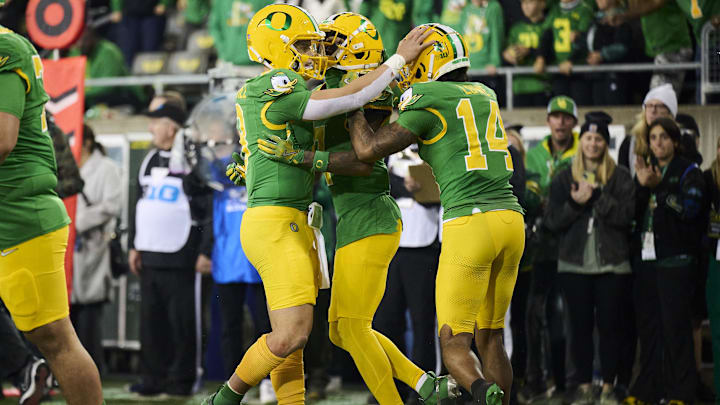 Nov 9, 2024; Eugene, Oregon, USA; Oregon Ducks quarterback Dillon Gabriel (8), left, celebrates after throwing a touchdown pass to wide receiver Evan Stewart (7) during the second half against the Maryland Terrapins at Autzen Stadium. Helping to celebrate is wide receiver Justius Lowe (14). Mandatory Credit: Troy Wayrynen-Imagn Images