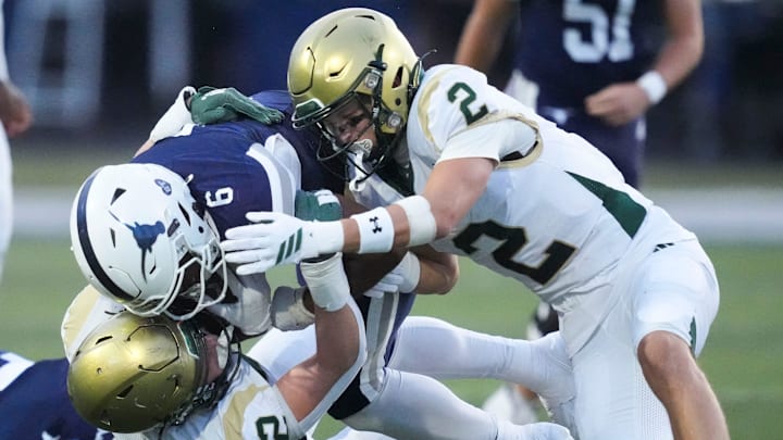 Anderson County's Jayzon Thompson (6) is brought down by Kaleb Johnson (32) and Brooks Johnston (2) in a TSSAA high school football game on August 28, 2025, in Clinton, Tennessee.