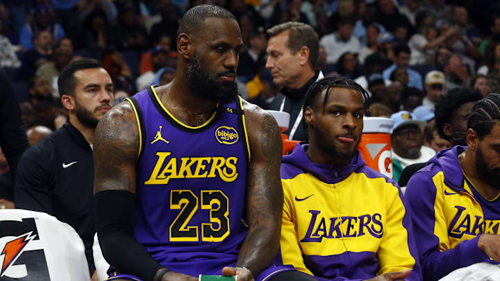 Los Angeles Lakers forward LeBron James and guard Bronny James sit on the bench.