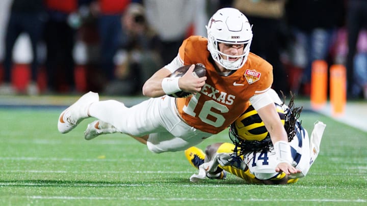 Dec 31, 2025; Orlando, FL, USA; Texas Longhorns quarterback Arch Manning (16) reaches with the ball for a first down while Michigan Wolverines defensive back Jordan Young (14) attempts to tackle during the second half at Camping World Stadium. Mandatory Credit: Matt Pendleton-Imagn Images