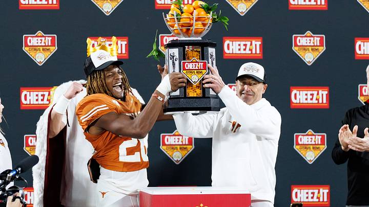 Texas Longhorns linebacker Ty'Anthony Smith (26) and head coach Steve Sarkisian raise the Cheez-It Citrus Bowl trophy after a game against the Michigan Wolverines at Camping World Stadium. 