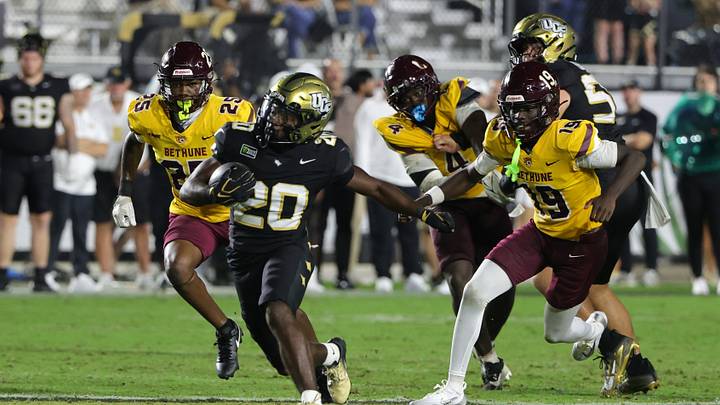 Sep 3, 2026; Orlando, Florida, USA;  Central Florida running back Kaj Baker (20) runs for a gain past Bethune-Cookman safety Cameron Anderson (19) during the fourth quarter at Acrisure Bounce House.  Mandatory Credit: Mike Watters-Imagn Images