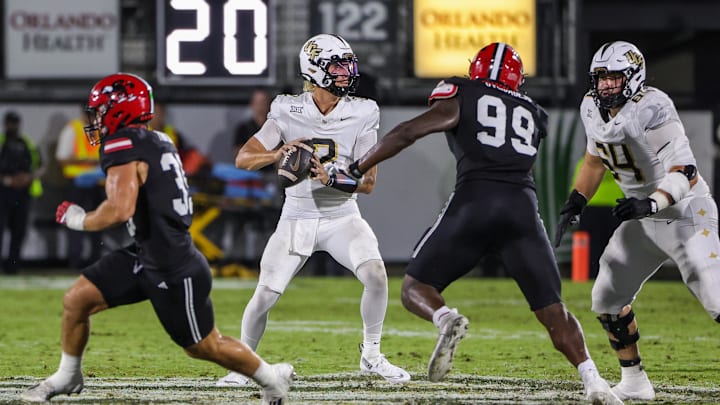 Aug 28, 2025; Orlando, Florida, USA; UCF Knights quarterback Tayven Jackson (2) rolls back to pass as Jacksonville State Gamecocks defensive end Emmanuel Oyebadejo (99) moves in during the second quarter at Acrisure Bounce House. Mandatory Credit: Mike Watters-Imagn Images