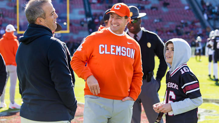Nov 29, 2025; Columbia, South Carolina, USA; 
Clemson Tigers head coach Dabo Swinney and South Carolina Gamecocks head coach Shane Beamer chat as Beamer’s son Hunter looks on before their game at Williams-Brice Stadium. Mandatory Credit: Jeff Blake-Imagn Images