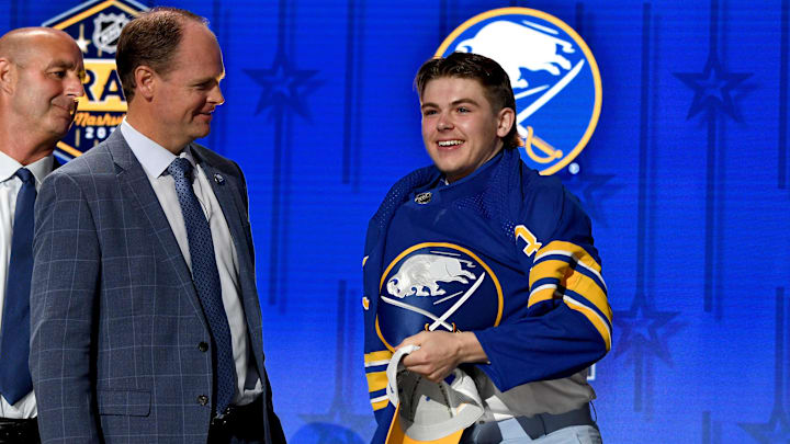 Jun 28, 2023; Nashville, Tennessee, USA; Buffalo Sabres draft pick Zach Benson puts on his sweater after being selected with the thirteenth pick in round one of the 2023 NHL Draft at Bridgestone Arena. Mandatory Credit: Christopher Hanewinckel-Imagn Images