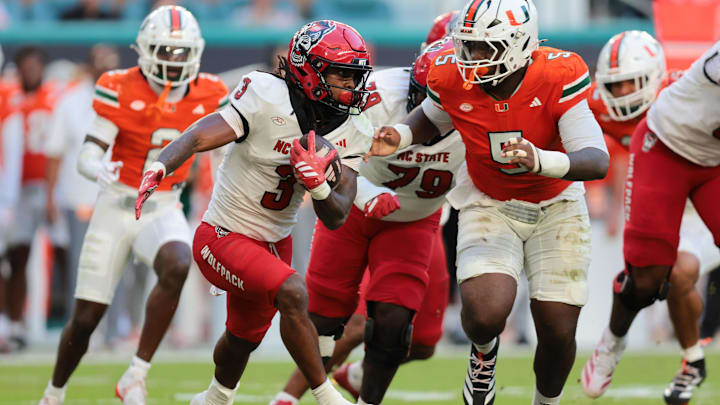 Nov 15, 2025; Miami Gardens, Florida, USA; NC State Wolfpack running back Hollywood Smothers (3) carries the football against Miami Hurricanes defensive lineman Justin Scott (5) during the second quarter at Hard Rock Stadium. Mandatory Credit: Sam Navarro-Imagn Images Nov 15, 2025; Miami Gardens, Florida, USA; NC State Wolfpack running back Hollywood Smothers (3) carries the football against Miami Hurricanes defensive lineman Justin Scott (5) during the second quarter at Hard Rock Stadium. Mandatory Credit: Sam Navarro-Imagn Images