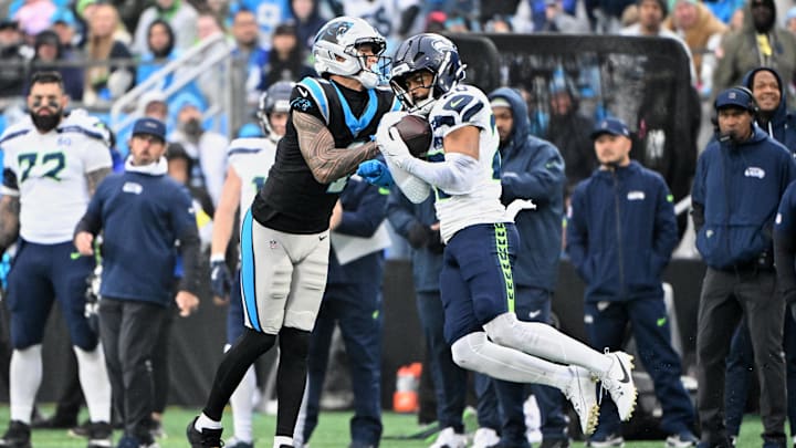 Dec 28, 2025; Charlotte, North Carolina, USA; Seattle Seahawks safety Julian Love (20) intercepts a pass intended for Carolina Panthers wide receiver Tetairoa McMillan (4) during the third quarter at Bank of America Stadium. 