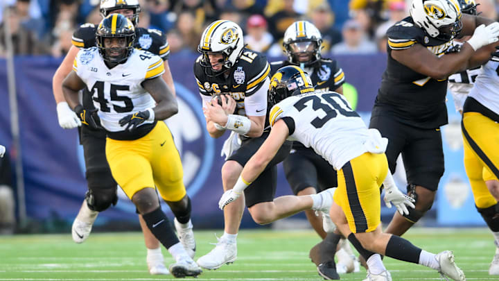 Dec 30, 2024; Nashville, TN, USA;  Missouri Tigers quarterback Brady Cook (12) runs the ball against the Iowa Hawkeyes during the first half at Nissan Stadium. Mandatory Credit: Steve Roberts-Imagn Images