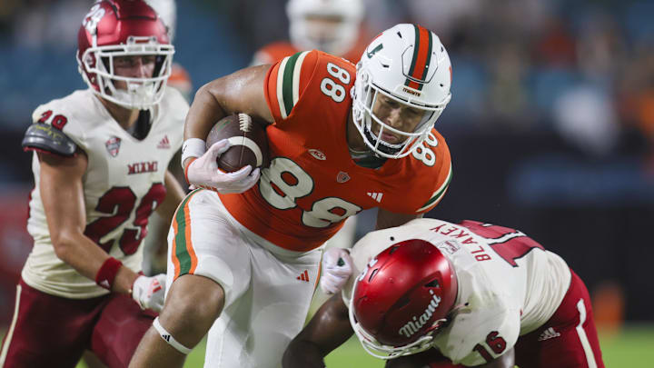 Sep 1, 2023; Miami Gardens, Florida, USA; Miami Hurricanes tight end Riley Williams (88) runs with the football as Miami Redhawks defensive back Eli Blakey (16) attempts a tackle during the fourth quarter at Hard Rock Stadium. Mandatory Credit: Sam Navarro-Imagn Images