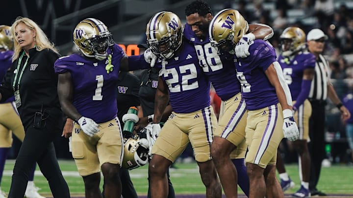 Tight end Quentin Moore is helped off the field by his UW teammates. 