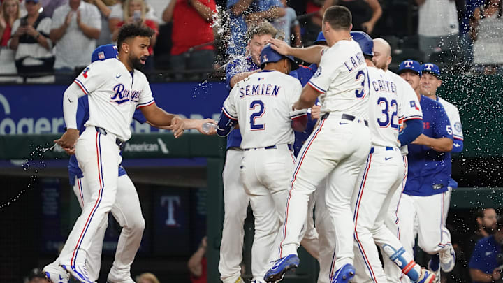 Jul 26, 2025; Arlington, Texas, USA; Texas Rangers second baseman Marcus Semien (2) celebrates with teammates after hitting a walk-off RBI single during the tenth inning against the Atlanta Braves at Globe Life Field. 