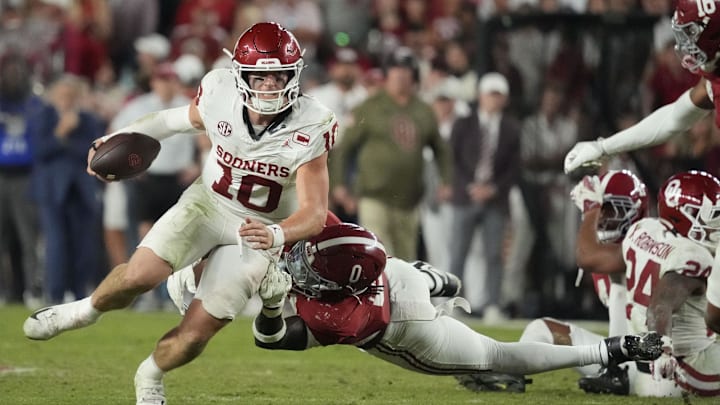 Nov 15, 2025; Tuscaloosa, Alabama, USA; Oklahoma Sooners quarterback John Mateer (10) tries to break free from a tackle by Alabama Crimson Tide linebacker Deontae Lawson (0) at Saban Field at Bryant-Denny Stadium. Oklahoma defeated Alabama 23-21. Mandatory Credit: Gary Cosby Jr.-Imagn Images Nov 15, 2025; Tuscaloosa, Alabama, USA; Oklahoma Sooners quarterback John Mateer (10) tries to break free from a tackle by Alabama Crimson Tide linebacker Deontae Lawson (0) at Saban Field at Bryant-Denny Stadium. Oklahoma defeated Alabama 23-21. Mandatory Credit: Gary Cosby Jr.-Imagn Images
