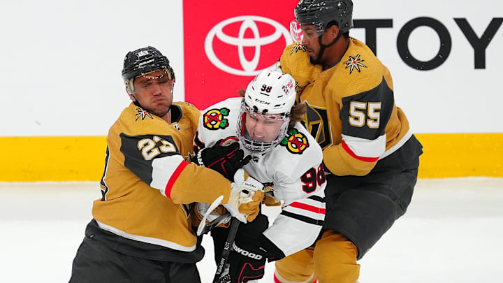 Apr 16, 2024; Las Vegas, Nevada, USA; Chicago Blackhawks center Connor Bedard (98) is checked by Vegas Golden Knights defenseman Alec Martinez (23) and right wing Keegan Kolesar (55) during the first period at T-Mobile Arena. Mandatory Credit: Stephen R. Sylvanie-Imagn Images