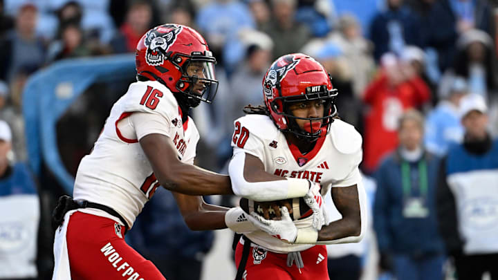 Nov 30, 2024; Chapel Hill, North Carolina, USA; North Carolina State Wolfpack quarterback CJ Bailey (16) hands the ball off to running back Hollywood Smothers (20) the ball in the first quarter at Kenan Memorial Stadium. Mandatory Credit: Bob Donnan-Imagn Images